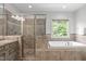 Well-lit bathroom featuring a separate shower and soaking tub beneath a bright window at 103 Woodland Ridge Ct, Cary, NC 27519