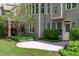 Backyard patio area with lush landscaping, featuring green siding and multiple windows at 103 Woodland Ridge Ct, Cary, NC 27519