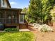 Exterior view of the backyard featuring a porch, stairs, lush grass, and flowering plants, ideal for outdoor living at 107 Whitby Ct, Cary, NC 27511