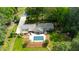 Aerial view displays a home with an inviting pool, screened patio, and large patio space surrounded by mature trees and landscaping at 11 Pine Forest Dr, Siler City, NC 27344