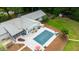 Aerial view displays a home with an inviting pool, screened patio, and large patio space surrounded by mature trees and landscaping at 11 Pine Forest Dr, Siler City, NC 27344