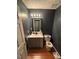 Stylish half bathroom with wood floors, gray walls, vanity, and modern light fixture at 1211 Odyssey Dr, Durham, NC 27713