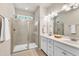 Bright bathroom featuring a double vanity with white cabinetry and a tiled glass-enclosed shower with a window for natural light at 1230 Wingstem Pl, Raleigh, NC 27607