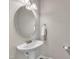Bathroom features a pedestal sink, oval mirror, and modern fixtures at 1230 Wingstem Pl, Raleigh, NC 27607