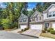 Street view of well-maintained townhomes with two-car garages, stone accents, and mature trees at 1230 Wingstem Pl, Raleigh, NC 27607