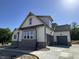 Exterior view of a modern home with a three-car garage and stone accents along the side and rear of the house at 1403 Cottondale Lane, Wake Forest, NC 27587