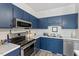 Close-up of a kitchen featuring blue cabinets, stainless steel appliances, and white countertops at 1601 Dunraven Dr, Raleigh, NC 27612