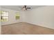 Neutral carpeted bedroom with two windows and a ceiling fan with light fixture at 2024 Spring Creek Dr, Durham, NC 27704