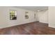 Bright open living room with hardwood floors, neutral walls, two large windows, and outside access at 2024 Spring Creek Dr, Durham, NC 27704