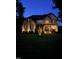 Stunning two-story home with beautiful brick and stone exterior, illuminated by landscape lighting at twilight at 2053 Monthaven Dr, Wake Forest, NC 27587