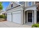 Close-up of a two-car garage and front door, accented by manicured landscaping at 209 Oswego Ct, Morrisville, NC 27560