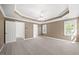 Spacious bedroom featuring carpet, tray ceiling, ceiling fan, and natural light from windows at 210 Highlands Lake Dr, Cary, NC 27518