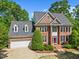 Traditional brick home features dormer windows, manicured landscaping and attached two car garage at 210 Highlands Lake Dr, Cary, NC 27518
