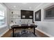 Modern home office with sleek black desk, dual monitors, minimalist decor, and bright natural light from a window at 213 North Crest Dr, Chapel Hill, NC 27517