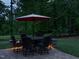 Charming backyard featuring an outdoor dining set under an umbrella, lit for evening enjoyment at 2317 Emerald Woods Dr, Wake Forest, NC 27587