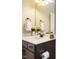 Cozy bathroom with a dark wood cabinet, framed mirror, single vanity, and elegant lighting at 2317 Emerald Woods Dr, Wake Forest, NC 27587
