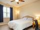 Neutral bedroom featuring a plush bed, side table with a lamp, and large window with blue curtains at 2317 Emerald Woods Dr, Wake Forest, NC 27587
