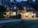 Rear exterior view of a beige two-story home with a three-car garage illuminated at dusk at 2317 Emerald Woods Dr, Wake Forest, NC 27587