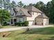 Rear exterior view of a beige two-story home with a three-car garage and well-kept lawn at 2317 Emerald Woods Dr, Wake Forest, NC 27587