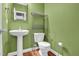Cozy half bath with pedestal sink, mirror, and storage shelf on the back of the toilet at 2418 Mont Haven Dr, Durham, NC 27712