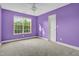 Cozy carpeted bedroom with a large window and purple walls, complete with a white ceiling fan at 2418 Mont Haven Dr, Durham, NC 27712