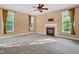 Large living room featuring a fireplace, natural light from three windows, and neutral carpeting at 2418 Mont Haven Dr, Durham, NC 27712
