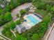 Aerial view of community pool, playground, parking and pool house surrounded by lush trees at 2832 Cameron Pond Dr, Cary, NC 27519