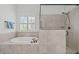 A separate tub and shower, encased in ceramic tile, with a window bringing natural light into the bathroom at 2832 Cameron Pond Dr, Cary, NC 27519