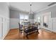 Formal dining room with wainscoting, modern lighting, and wood floors adjacent to a door leading to the outside at 30 Devilwood Dr, Four Oaks, NC 27524