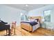 Bright bedroom featuring a rattan bed frame, hardwood floors, and dual windows at 301 Georgetown Rd, Raleigh, NC 27608