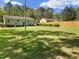 Expansive grassy backyard bordered by mature trees, with a quaint house providing the perfect backdrop for outdoor enjoyment at 3016 Fields Dr, Raleigh, NC 27603