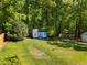 A charming storage shed in a backyard setting, surrounded by trees and green grass at 3016 Fields Dr, Raleigh, NC 27603