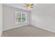 Simple bedroom featuring neutral carpet, a ceiling fan, and a large window, creating a comfortable, inviting space at 308 Ravenstone Dr, Cary, NC 27518