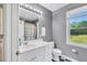 Well-lit bathroom with white vanity, mirror, and views of the green outdoors at 3214 Saddle Club Rd, Mebane, NC 27302