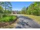 Long, paved driveway winding up to a charming brick home surrounded by mature trees at 3214 Saddle Club Rd, Mebane, NC 27302