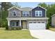 Beautiful two story home featuring a stone and blue shingle facade, a well manicured lawn and a two-car garage at 3804 Delves Ln, Raleigh, NC 27616