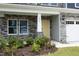 Close-up of the front porch featuring stone supports, a cream-colored door, manicured landscaping, and solar walkway lighting at 3804 Delves Ln, Raleigh, NC 27616