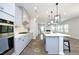 An open kitchen with gray cabinets, white countertops, a stainless steel oven, and an island with bar stool seating at 3804 Delves Ln, Raleigh, NC 27616