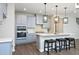 A kitchen island with seating and pendant lighting with grey cabinets, stainless appliances, and a tile backsplash at 3804 Delves Ln, Raleigh, NC 27616