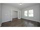 A bright, open room featuring wood flooring, gray walls, and a doorway with glass french doors, and many windows at 3804 Delves Ln, Raleigh, NC 27616