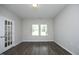 A bright, open room featuring wood flooring, gray walls, and a doorway with glass french doors, and bright windows at 3804 Delves Ln, Raleigh, NC 27616