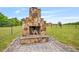 Outdoor stone fireplace with hearth and outdoor seating in fenced backyard on green lawn at 40 Senter Farm Ct, Fuquay Varina, NC 27526