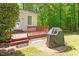 Backyard featuring a wood deck with a grill on a patio, surrounded by green lawn and mature trees at 4012 Graham Newton Rd, Raleigh, NC 27606