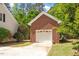 A brick detached garage featuring a classic white garage door, framed by lush greenery at 4012 Graham Newton Rd, Raleigh, NC 27606
