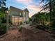 Back of house, featuring a stone patio, outdoor furniture, and lush landscaping at sunset at 4210 Falls River Ave, Raleigh, NC 27614