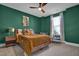 Green painted bedroom featuring a bed with gold bedding, a plush chair and a unique decor at 4816 Heathshire Dr, Raleigh, NC 27616