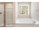 Bathroom showcasing a soaking tub, a large window, and a shower stall at 5516 Jaeger Dr # 75, Graham, NC 27253