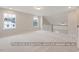 Spacious loft area with neutral carpeting, large windows providing natural light, and a staircase with white railing at 5516 Jaeger Dr # 75, Graham, NC 27253
