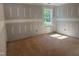 Empty room under construction featuring a single window, exposed plywood flooring, and prepped walls ready for finishing touches at 5516 Jaeger Dr # 75, Graham, NC 27253
