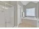 Bright bathroom featuring a glass shower, soaking tub, and neutral tile flooring at 602 Alden Bridge Dr, Cary, NC 27519